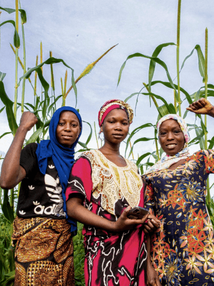 three african women posing in a field